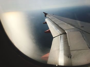 Close-up of airplane wing against sky during sunset