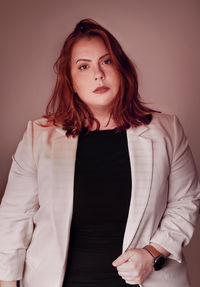 Portrait of beautiful young woman standing against wall