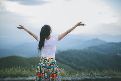 Rear view of woman standing on mountain against sky