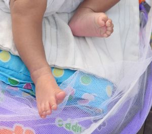 Low section of baby lying on bed