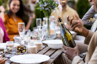 Midsection of woman drinking glass on table