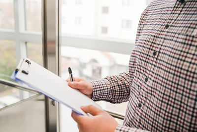 Midsection of man holding paper at home