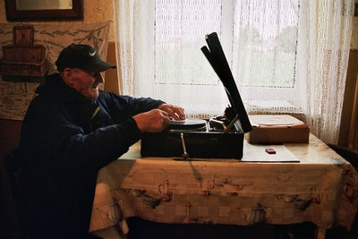 Side view of man sitting on table at home