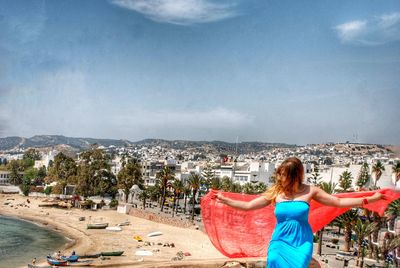 Rear view of woman standing against sky in city