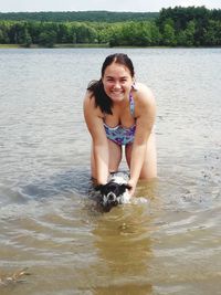 Portrait of smiling young woman with dog at lake