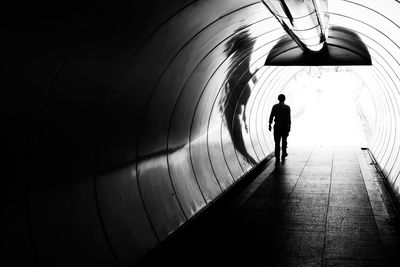 Silhouette of man walking in tunnel