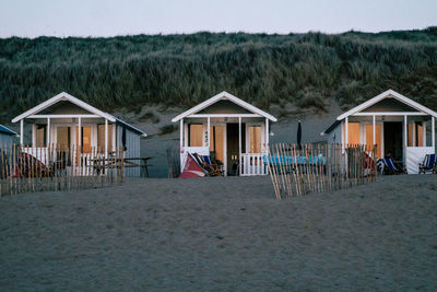 House on beach by building against sky