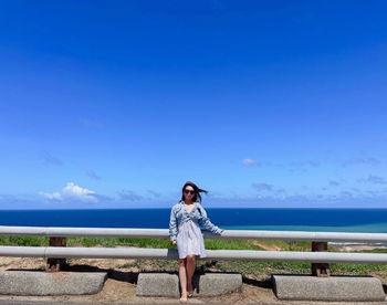 Woman standing by sea against blue sky