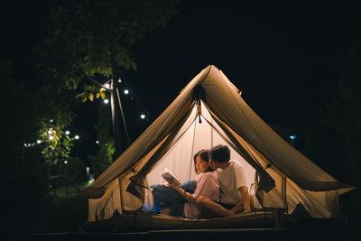 Asian couple relax and reading book in camping tent on summer vacation