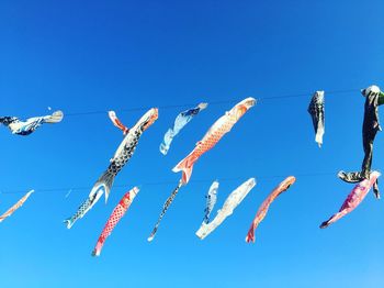 Low angle view of paper fish hanging against blue sky