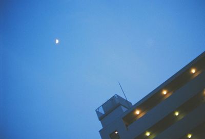 Low angle view of illuminated moon against blue sky