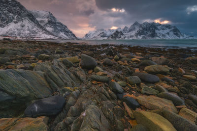 Rocks on beach against sky during sunset