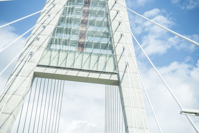 Low angle view of bridge against buildings in city against sky