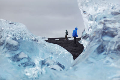 People in sea against sky during winter