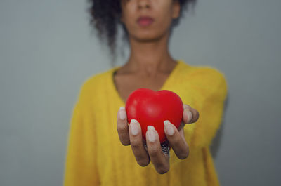 Selective focus on the hand of a black woman offering a heart shape