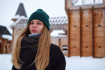 Portrait of young woman with long hair standing outdoors during winter