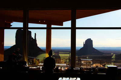 Rear view of silhouette man standing in restaurant against window