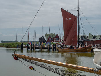 Sailboats moored at harbor against sky