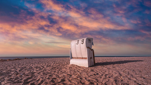 Low angle view of bag on beach by sea against sky during sunset