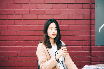 Portrait of a beautiful young woman against brick wall