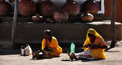 Women looking away sitting on footpath 