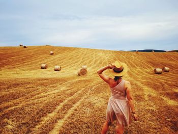 Rear view of woman standing on field against sky