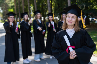 Portrait of woman wearing graduation gown standing in city