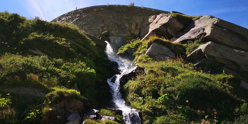 Low angle view of waterfall against sky