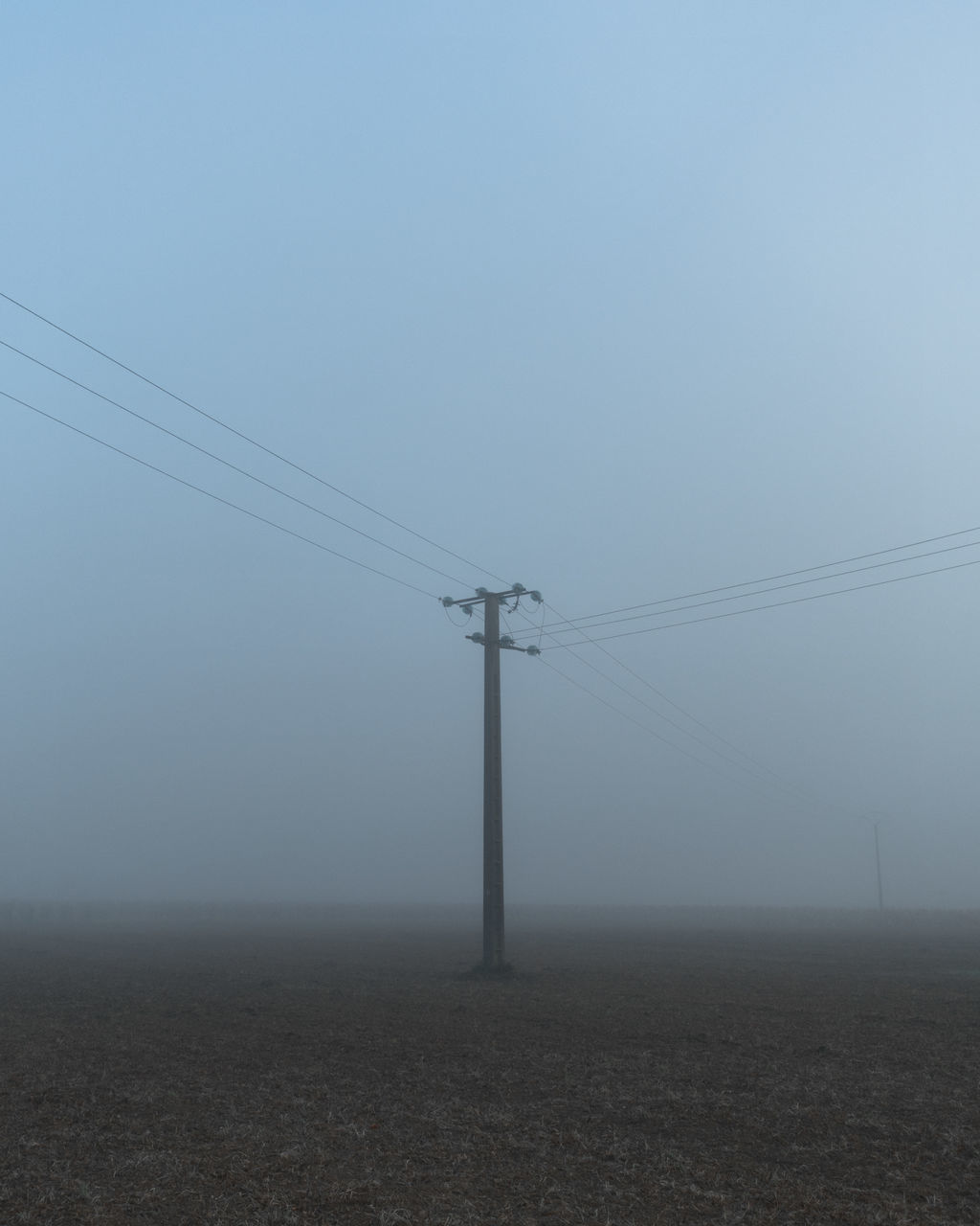 cable, electricity, technology, electricity pylon, power line, power supply, sky, power generation, wind, nature, fog, line, no people, horizon, environment, landscape, overhead power line, land, scenics - nature, copy space, day, tranquility, outdoors, telephone line, transmission tower, beauty in nature, tranquil scene, transportation, field, remote, telephone pole, haze, rural scene