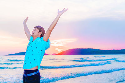 Full length of woman standing on beach against sky during sunset