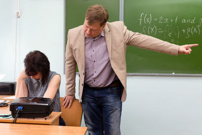 The director scolds the teacher for an unfulfilled task and throws him out of the classroom 