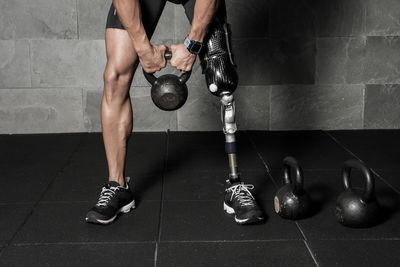 Low section of disabled man exercising with kettlebell at gym