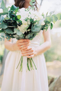 Midsection of bride holding bouquet