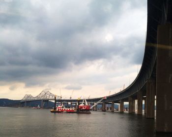 Bridge over river against cloudy sky