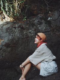 Side view of young woman sitting on rock