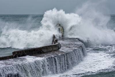 Large waves breaking at the end of a pier.
