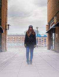 Full length portrait of man standing against sky in city