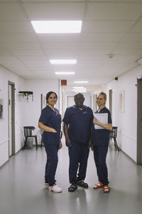 Smiling male doctor standing with female colleagues at healthcare center