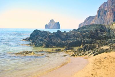 Rock formations on beach against sky