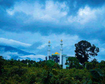 Tower amidst trees and buildings against sky