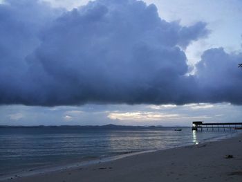 View of calm beach against cloudy sky