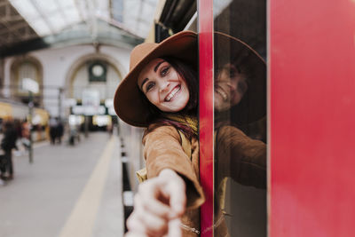 Portrait of smiling woman standing at entrance of train