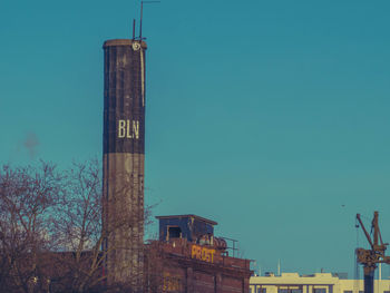 Low angle view of water tower against clear blue sky