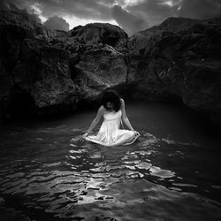 Full length of woman standing on rock by sea