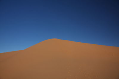 Scenic view of desert against clear blue sky