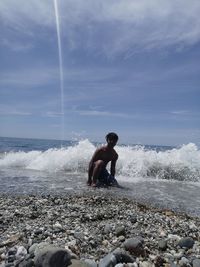 Rear view of man on beach against sky