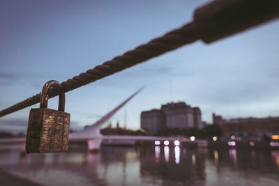 Close-up of padlocks on bridge over river against sky