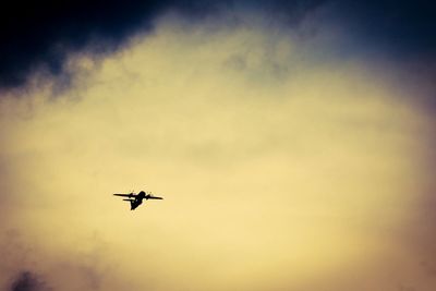 Low angle view of silhouette airplane against sky during sunset