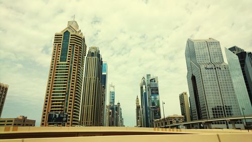 Low angle view of skyscrapers against cloudy sky