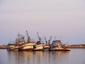 Sailboats moored in sea against clear sky